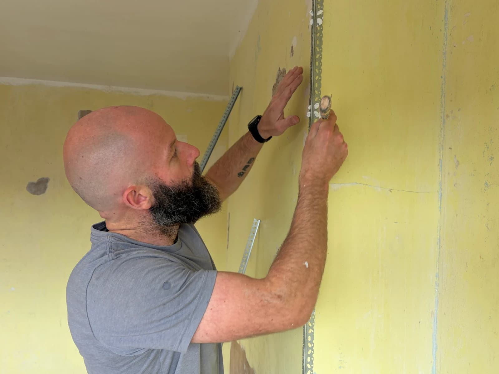Plasterer fitting a corner bead to the bedroom window reveal