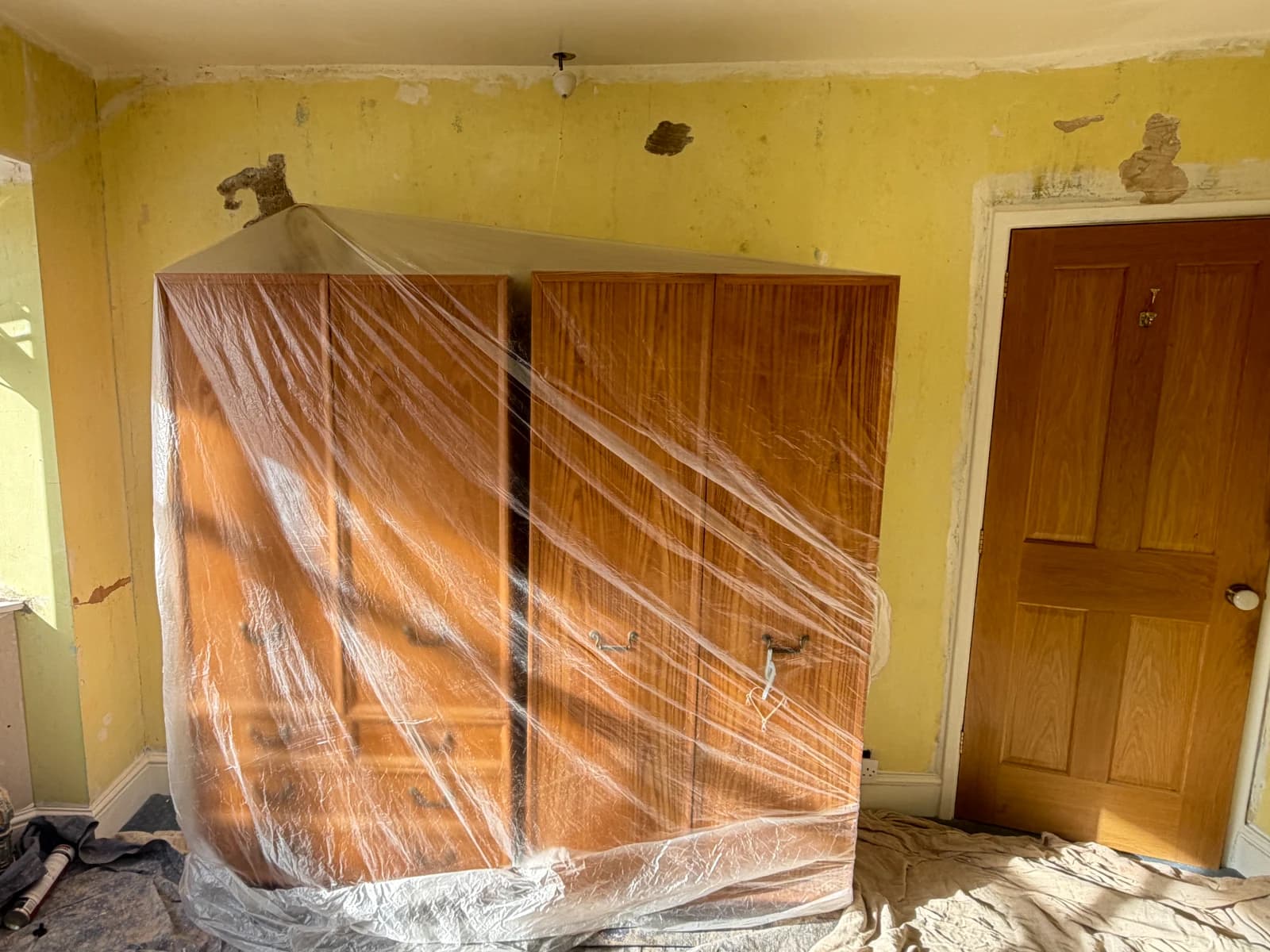 Wardrobe covered with protective sheeting and floor covered before bedroom plastering