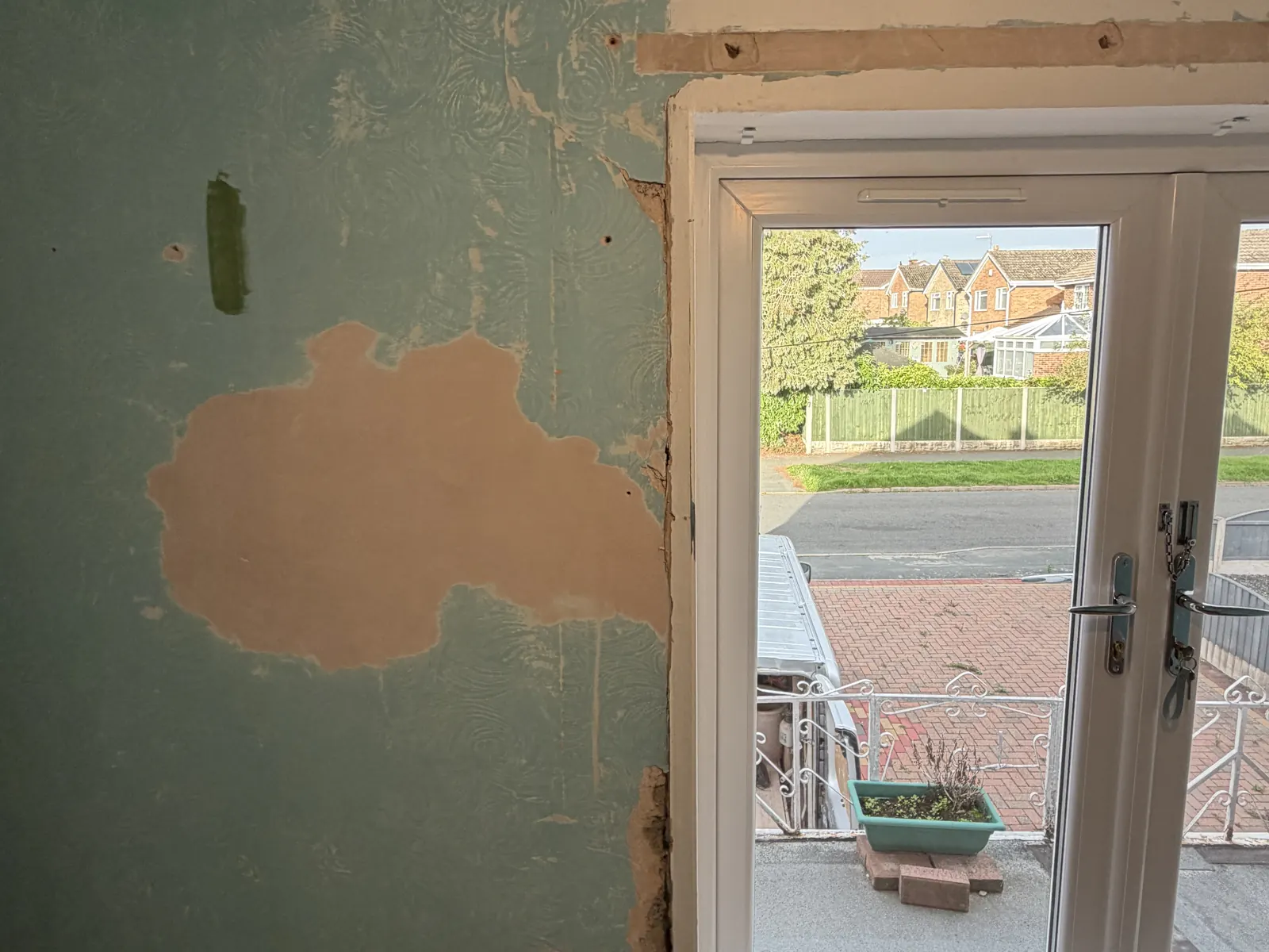 Damaged plaster and an old patch repair on the bedroom end wall beside the glazed doors