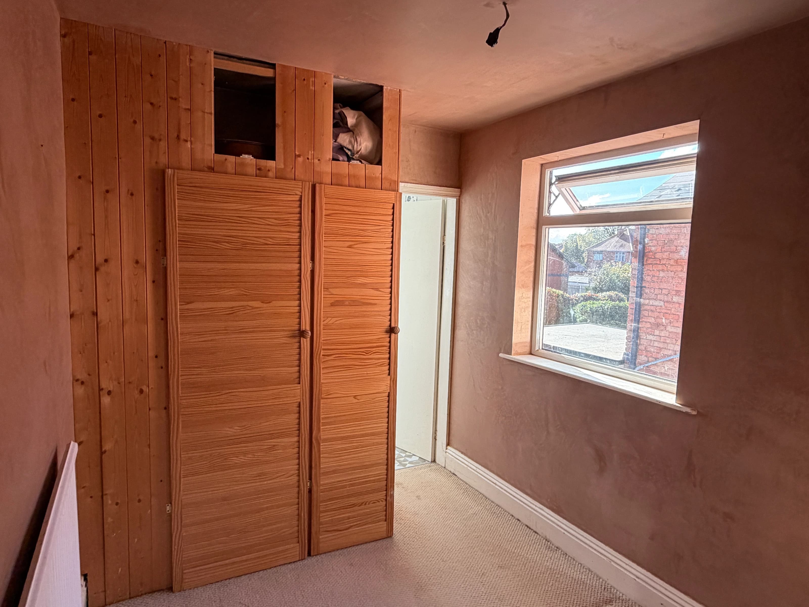 Freshly skimmed ceiling and window wall beside the timber wardrobe in the Alvaston bedroom