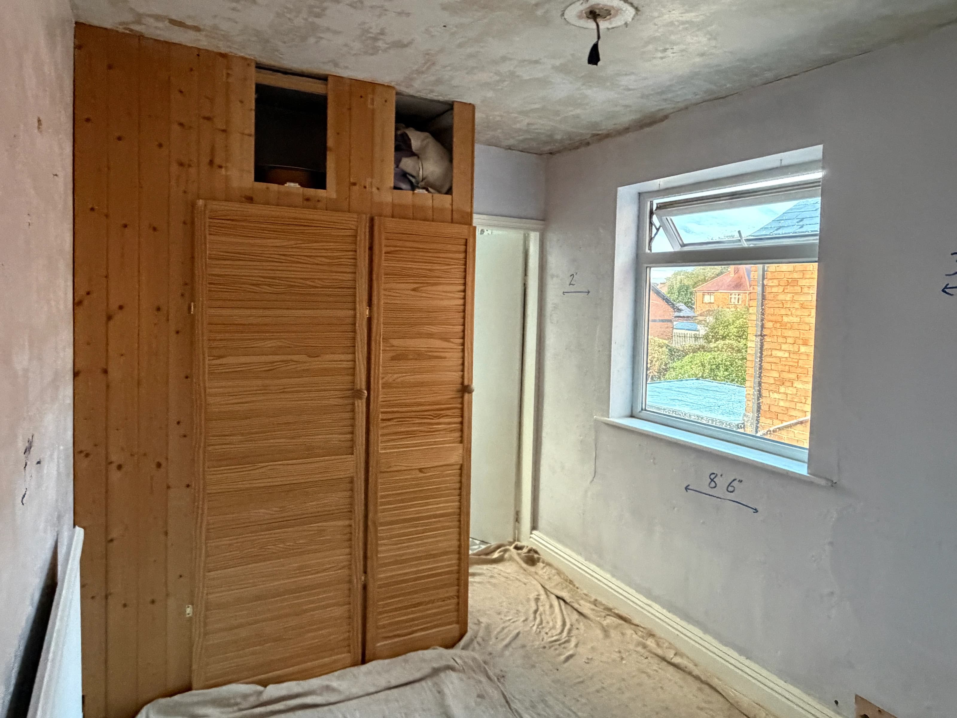 Alvaston bedroom before plastering, showing the original ceiling and window wall beside the timber wardrobe