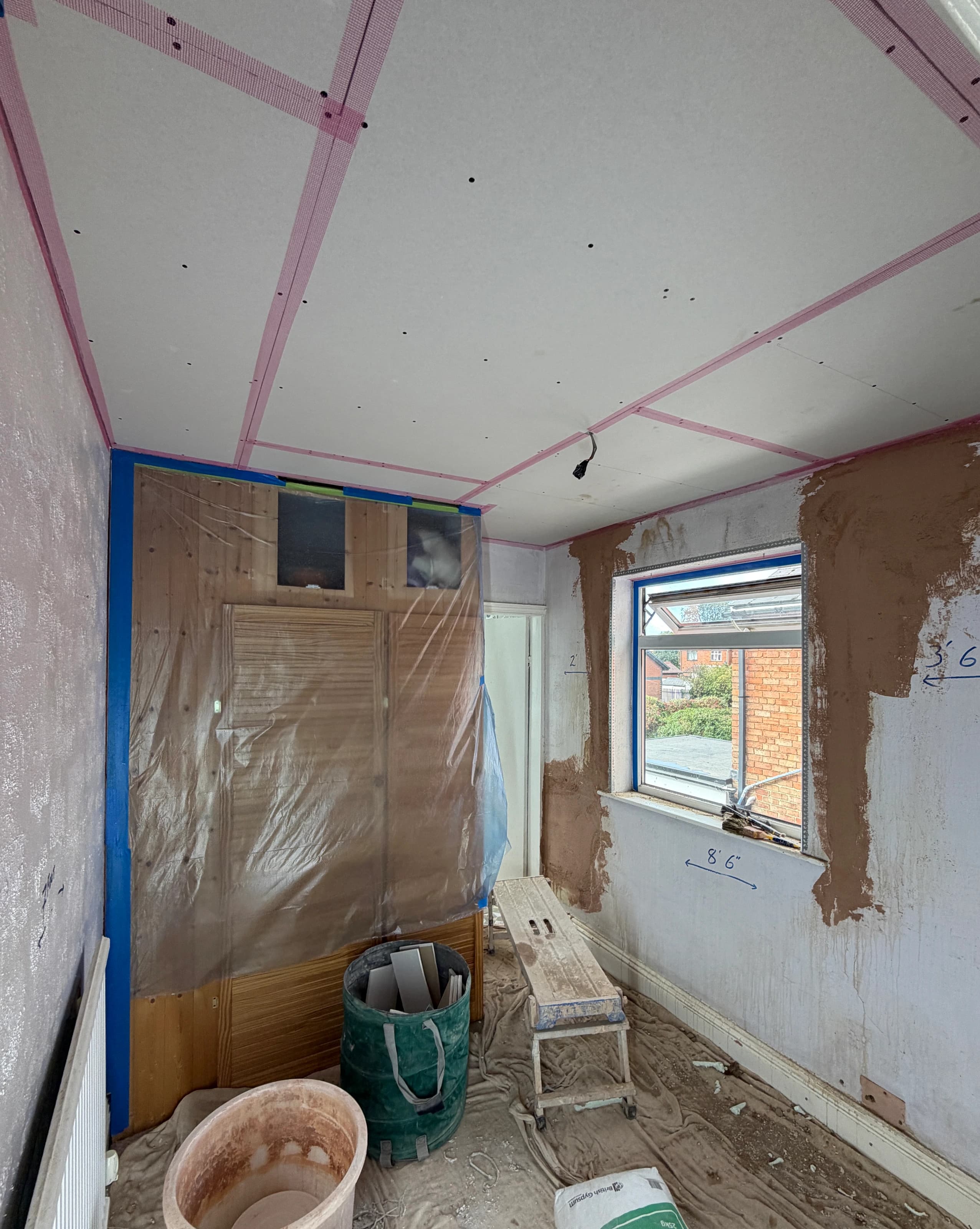 New ceiling plasterboard with taped joints above the protected wardrobe in the Alvaston bedroom